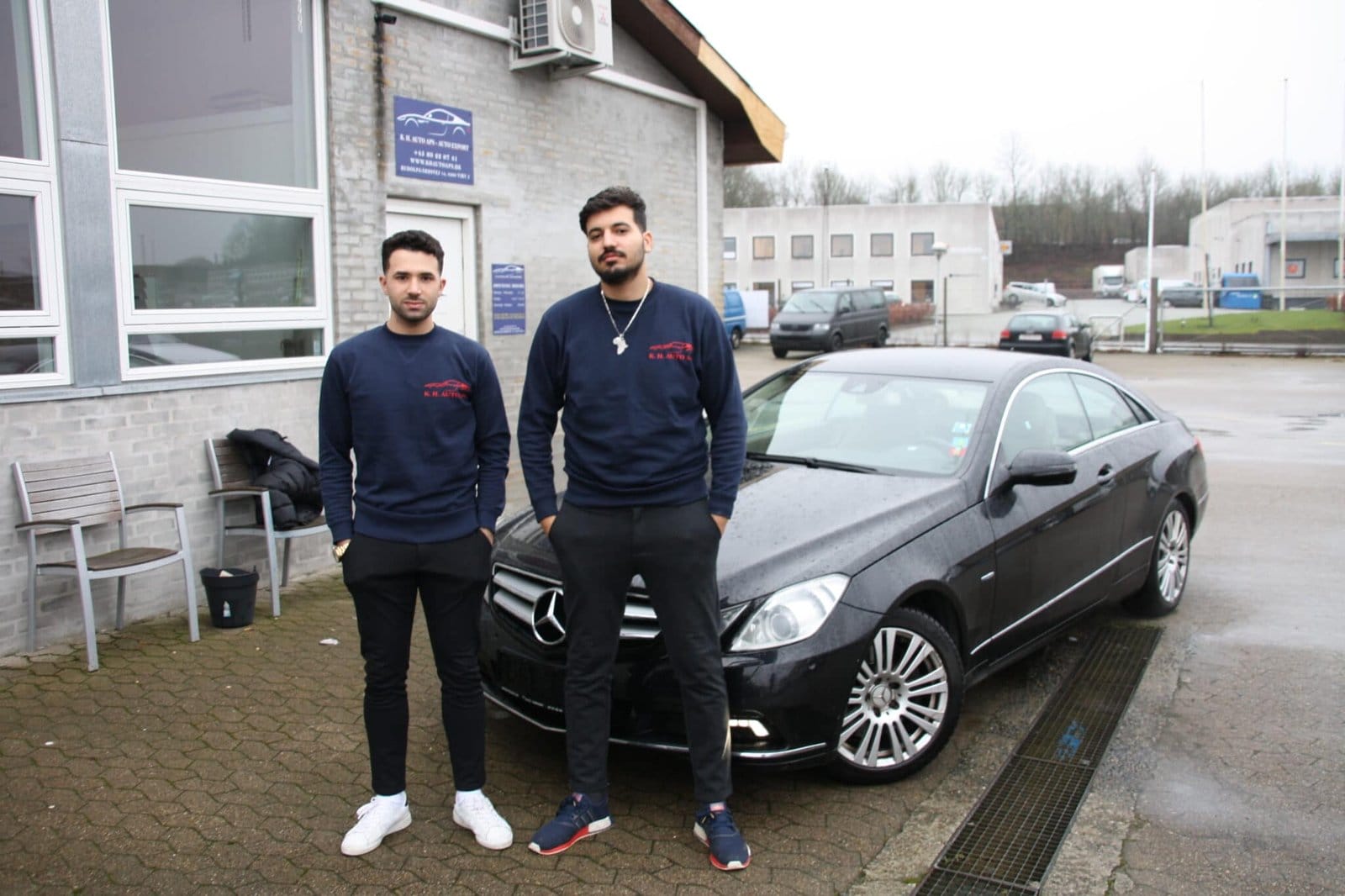 To mænd foran sort Mercedes ved autoværksted